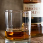 Glass of Famous Grouse whiskey with bottle in the background