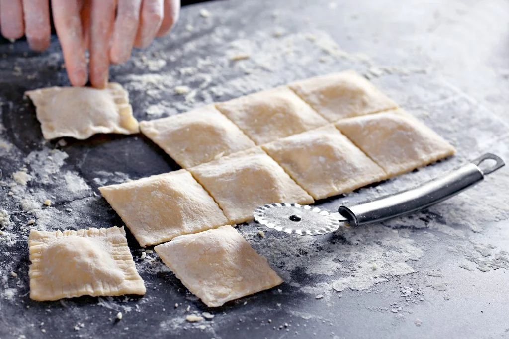 Woman making ravioli on table