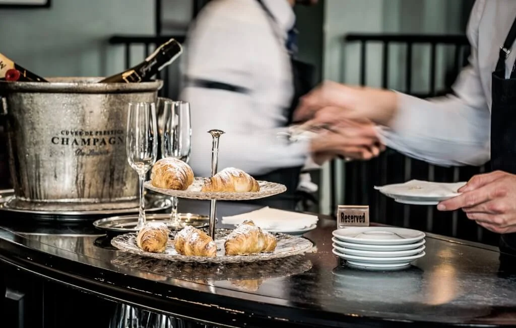 Paris cafe with waiter serving pastries and champagne