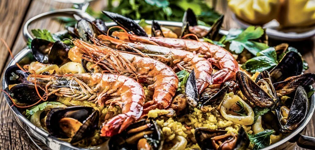 Traditional seafood paella in the pan on a wooden old table
