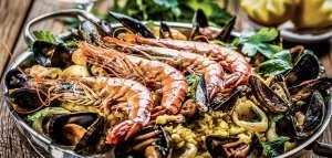 Traditional seafood paella in the pan on a wooden old table