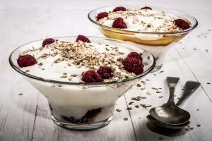 traditional scottish desserts, cranachan with raspberry, whipped cream and roasted oatmeal in a glass