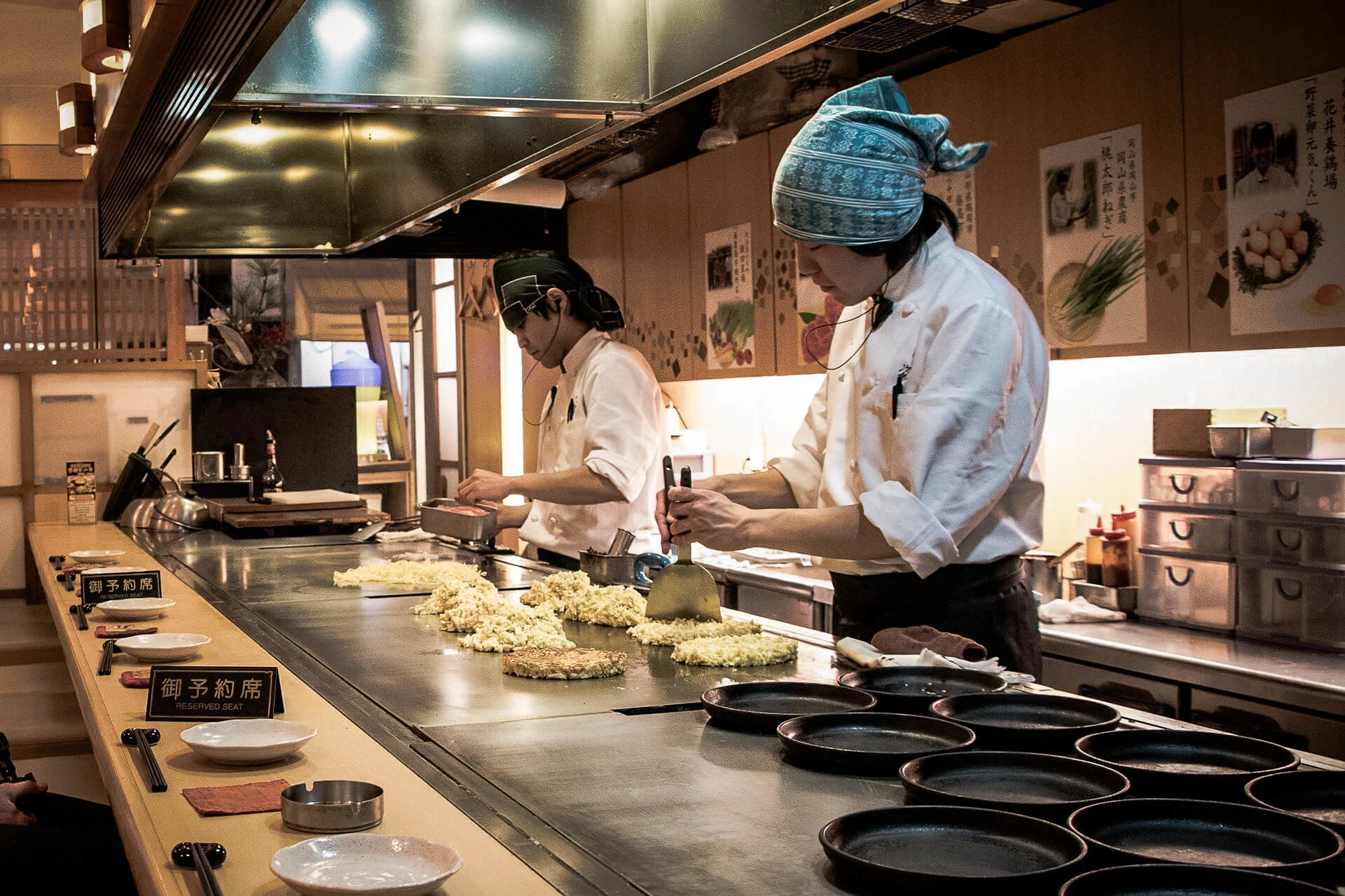 Two Japanese chefs in the kitchen making okonomiyaki
